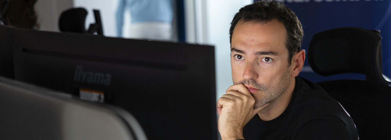 analyste SOC portant un t-shirt noir sns concentré sur son écran