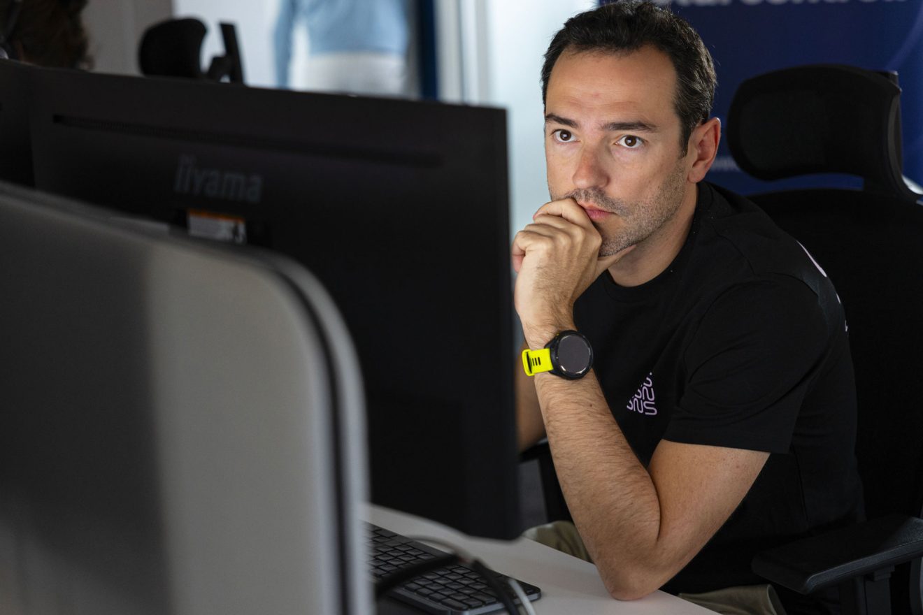 analyste SOC portant un t-shirt noir sns concentré sur son écran