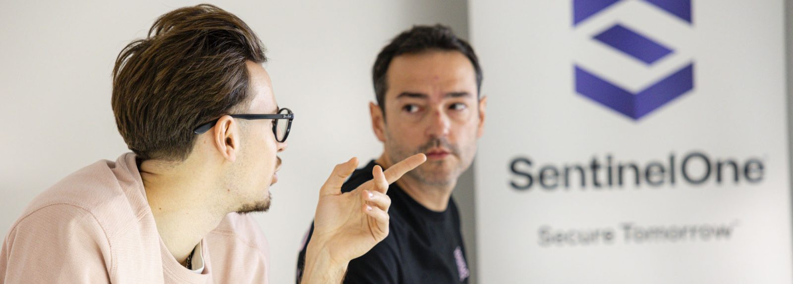 deux analystes SOC en réunion devant un kakémono Sentinelone