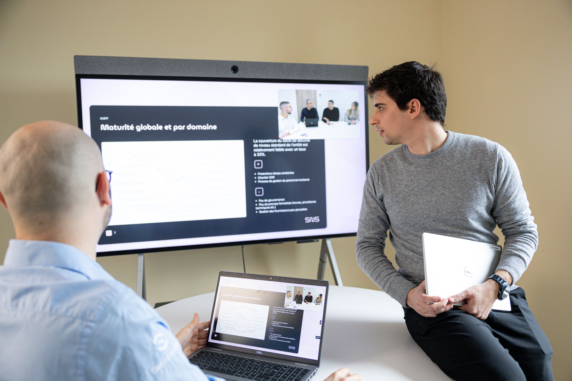 un pentesteur regardant un écran assis sur une table à côté d'un collaborateur de dos