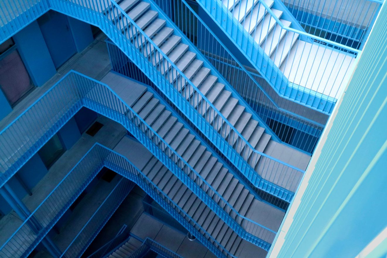 une cage d'escaliers de plusieurs niveaux vue plongeante dans un dégradé de bleu