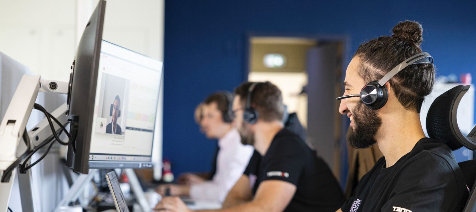 ingénieur support avec un casque qui sourit assis à son poste de travail