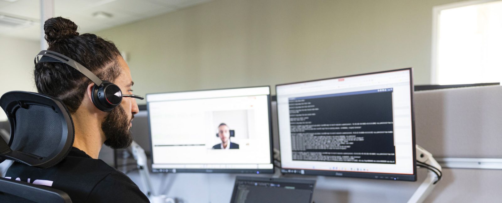 ingénieur support de dos avec un casque devant son ordinateur